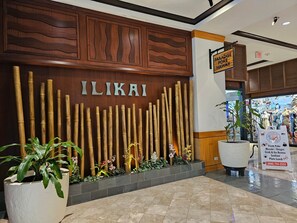 ILIKAI restaurant features a bamboo facade, potted plants, and a signboard showcasing fresh poke, musubi, and grab-and-go bentos.