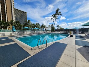 Relax by the pool surrounded by comfortable lounge chairs and shaded umbrellas.
