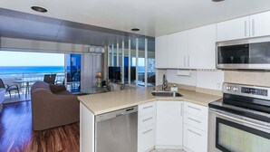 Una cucina moderna con vista sull'oceano, un'area pranzo con un divano e un balcone con tavolo e sedie.