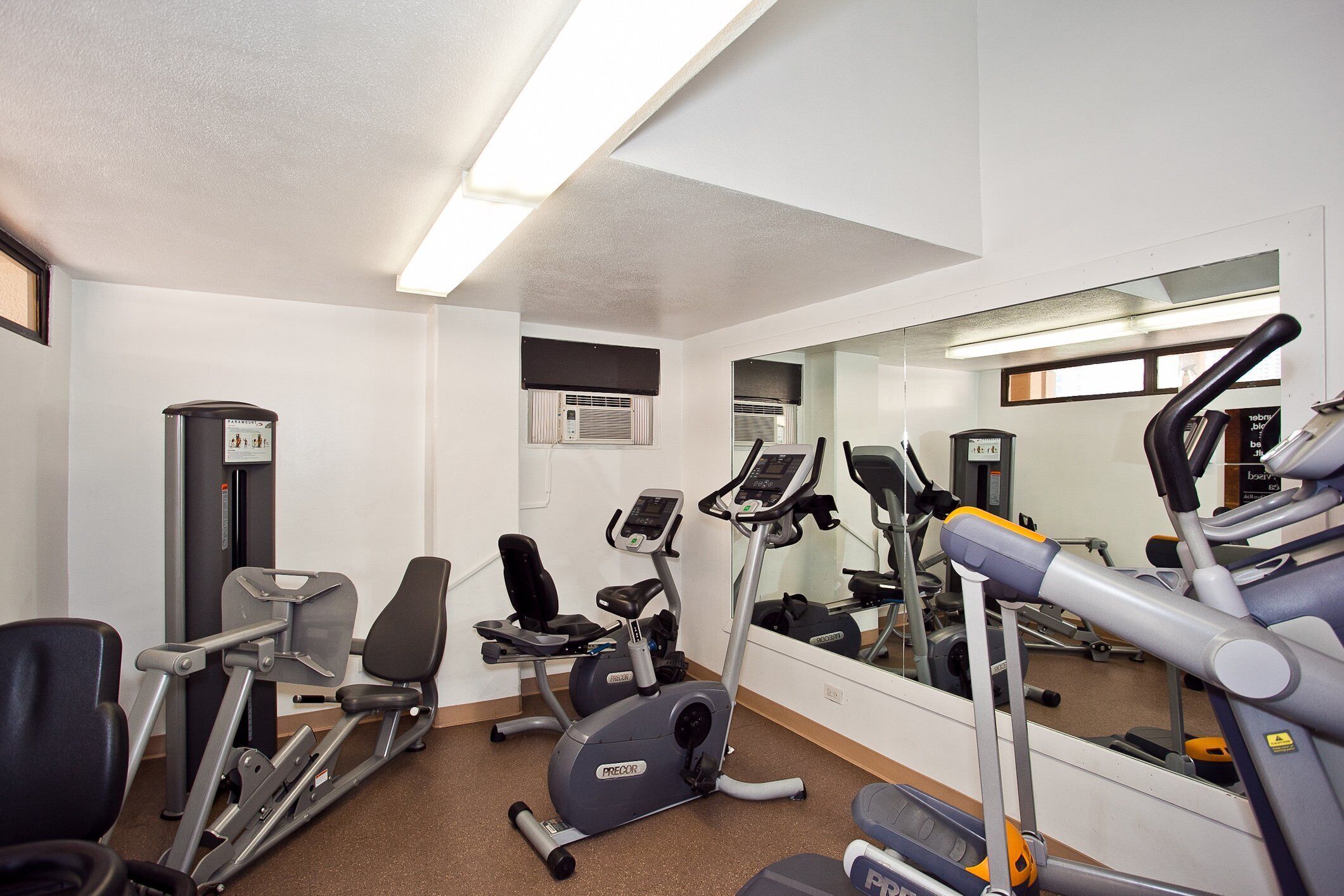 A gym with exercise equipment, a mirror, and a window.