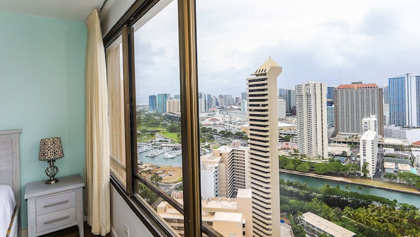 A room with a large window offering a view of a cityscape with high-rise buildings and a marina.