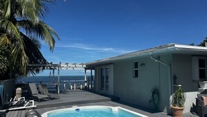 A pool area with a view of the ocean, lounge chairs, and a pergola. - Caribbean Sunsets: 3BR Home Gulf Views Pool & Dock (Marathon)