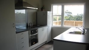 Una cocina moderna con armarios blancos, encimera negra y ventana con vistas a zonas verdes.