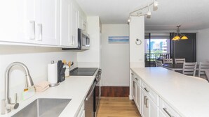 A modern kitchen with white cabinets, stainless steel appliances, and a wooden floor. - Relaxing, Spacious, Great Location In Waikiki! (Honolulu)