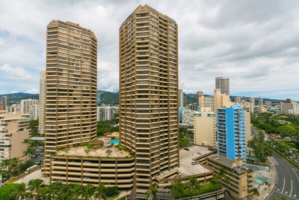 Experience the sleek, high-rise hotel with a unique curved facade and balconies overlooking a lush urban landscape.