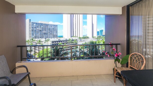 Un balcon offrant une vue sur de hauts immeubles et des palmiers.