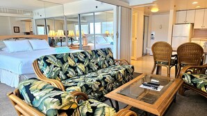 A hotel room with a bed, a sofa, a coffee table, and a dining area with chairs.