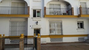 Un edificio residencial de varios pisos con balcones, arcos en las entradas y un acceso con portón.