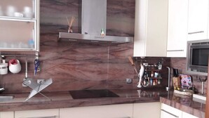 Una cocina moderna con armarios blancos, salpicadero de mármol y electrodomésticos de acero inoxidable.