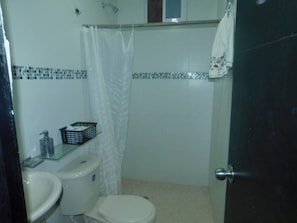 Bathroom features a toilet, sink, and shower with a decorative backsplash.