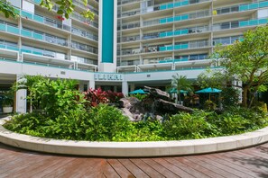 Un hotel de varios pisos con balcones, una fuente central y un jardín ajardinado.