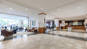 Un vestíbulo amplio con una recepción, zonas de estar y un mostrador de check-in.