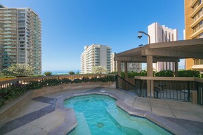 Relax by the rectangular pool surrounded by lush greenery and ocean views.