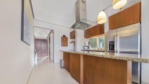 Una cucina moderna con isola centrale, elettrodomestici in acciaio inossidabile, mobili in legno e illuminazione a sospensione.