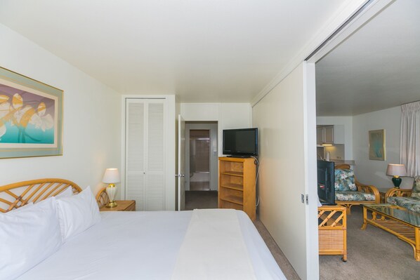 Ett hotellrum med en säng, en tv, en sittgrupp med bord och stolar samt ett badrum som syns genom en öppen dörr.