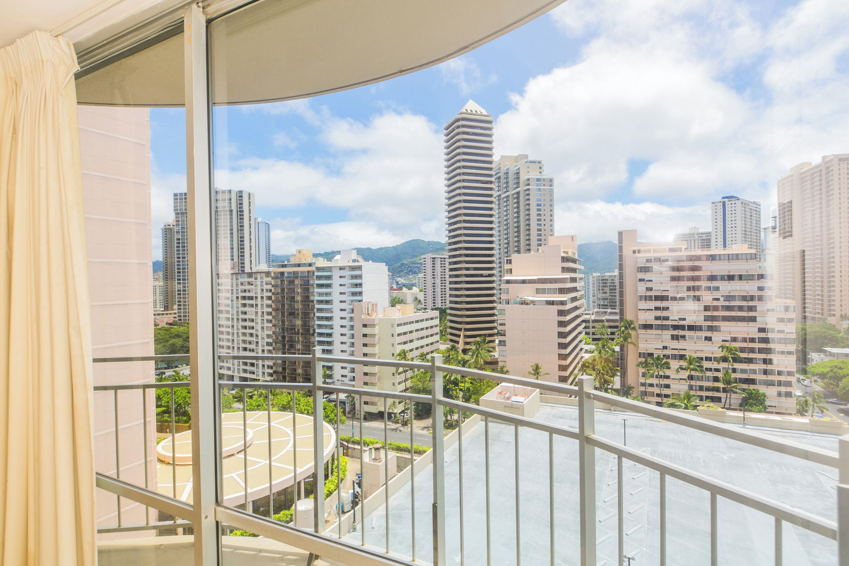 A high-rise building with a view of a cityscape, including other tall buildings and a mountain in the background.