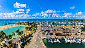 A marina with boats docked, a parking lot, and a beach with palm trees. - Desirable "44"; Stack At The Ilikai Hotel.  Unobstructed Ocean Views! (Honolulu)