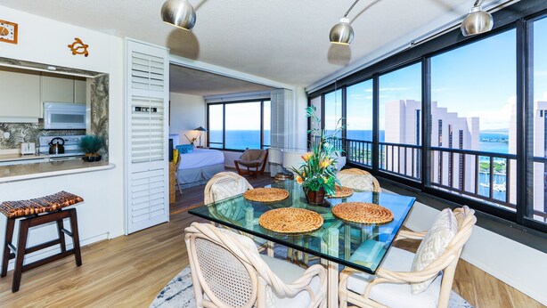 Ein modernes Wohnzimmer mit einem Glastisch, Korbstühlen und Blick auf die Stadt durch große Fenster.