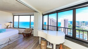 Ein Hotelzimmer mit Bett, Schreibtisch, Stuhl und Blick auf das Meer und die Stadt.