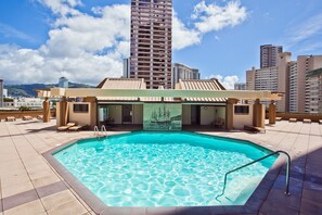 Une piscine sur le toit, dotée de chaises longues et offrant une vue sur les grands immeubles.