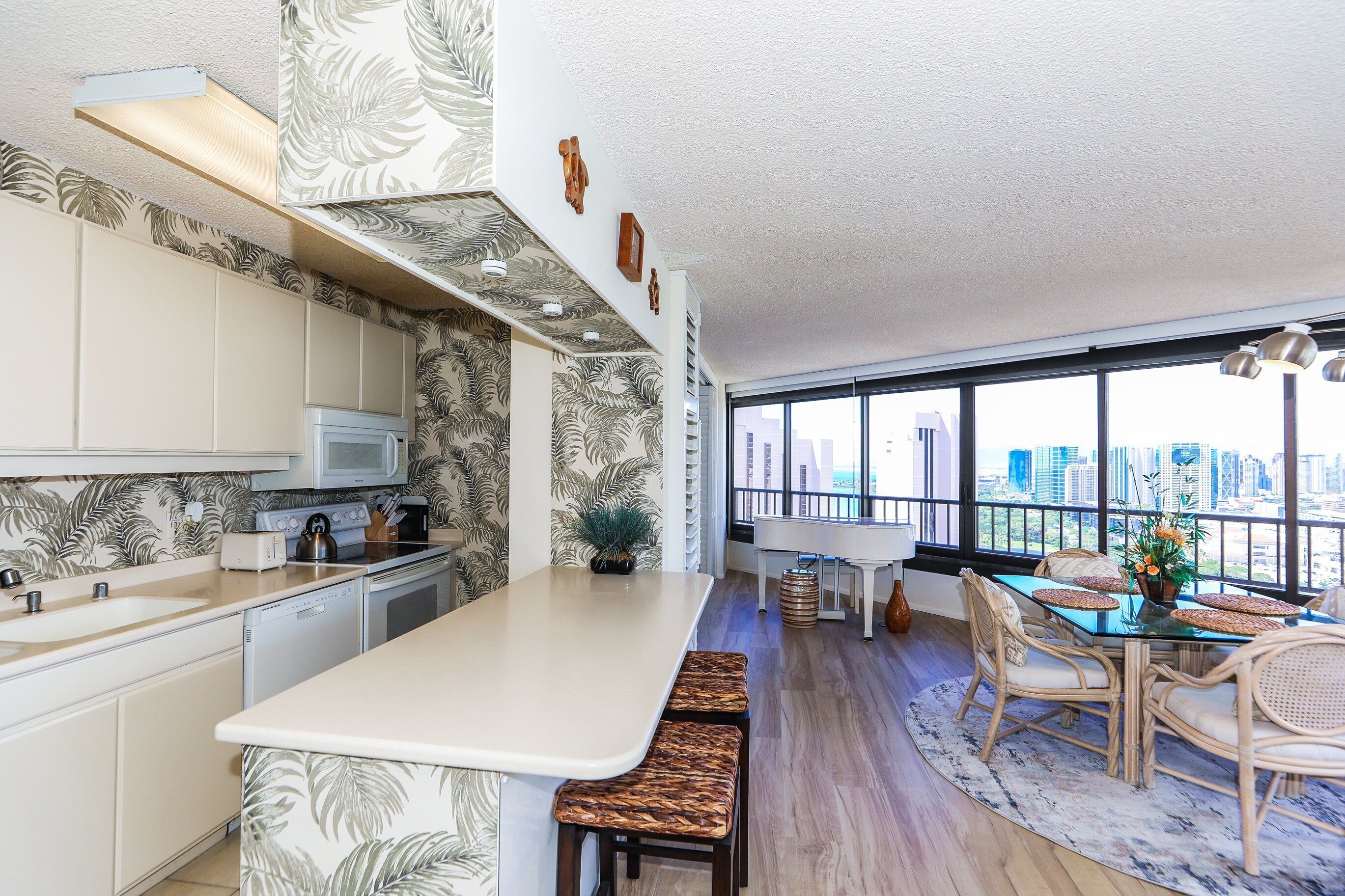 A modern kitchen with a large island, white cabinetry, and a view of the city through large windows.