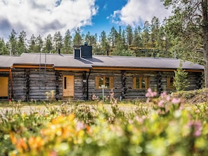 A log cabin with a sloped roof, multiple windows, and a chimney.