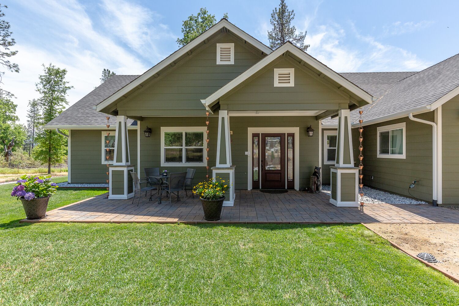 A two-story house with a front porch, a dining area, and a small garden.
