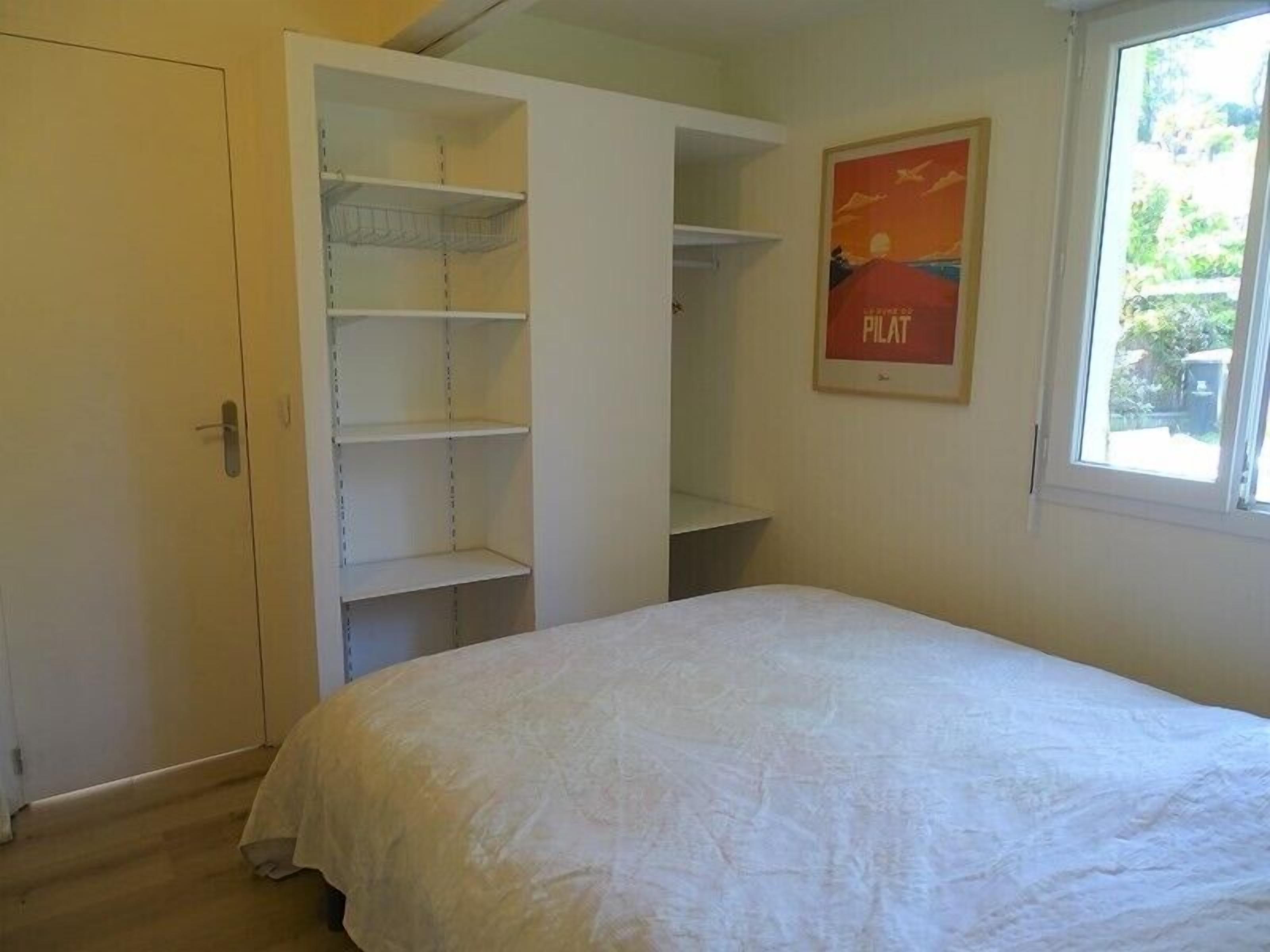 Um quarto com uma cama, um guarda-roupa e uma janela com vista.