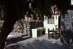 Relax in a serene outdoor space surrounded by lush greenery and a charming stone wall.