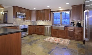 A modern kitchen with wooden cabinets, stainless steel appliances, and a large window.