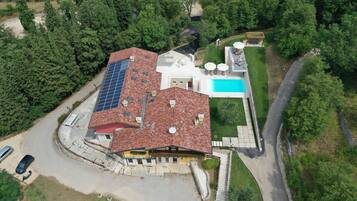 Ein Luftbild eines Hauses mit Swimmingpool, Solaranlage und gepflegtem Rasen.