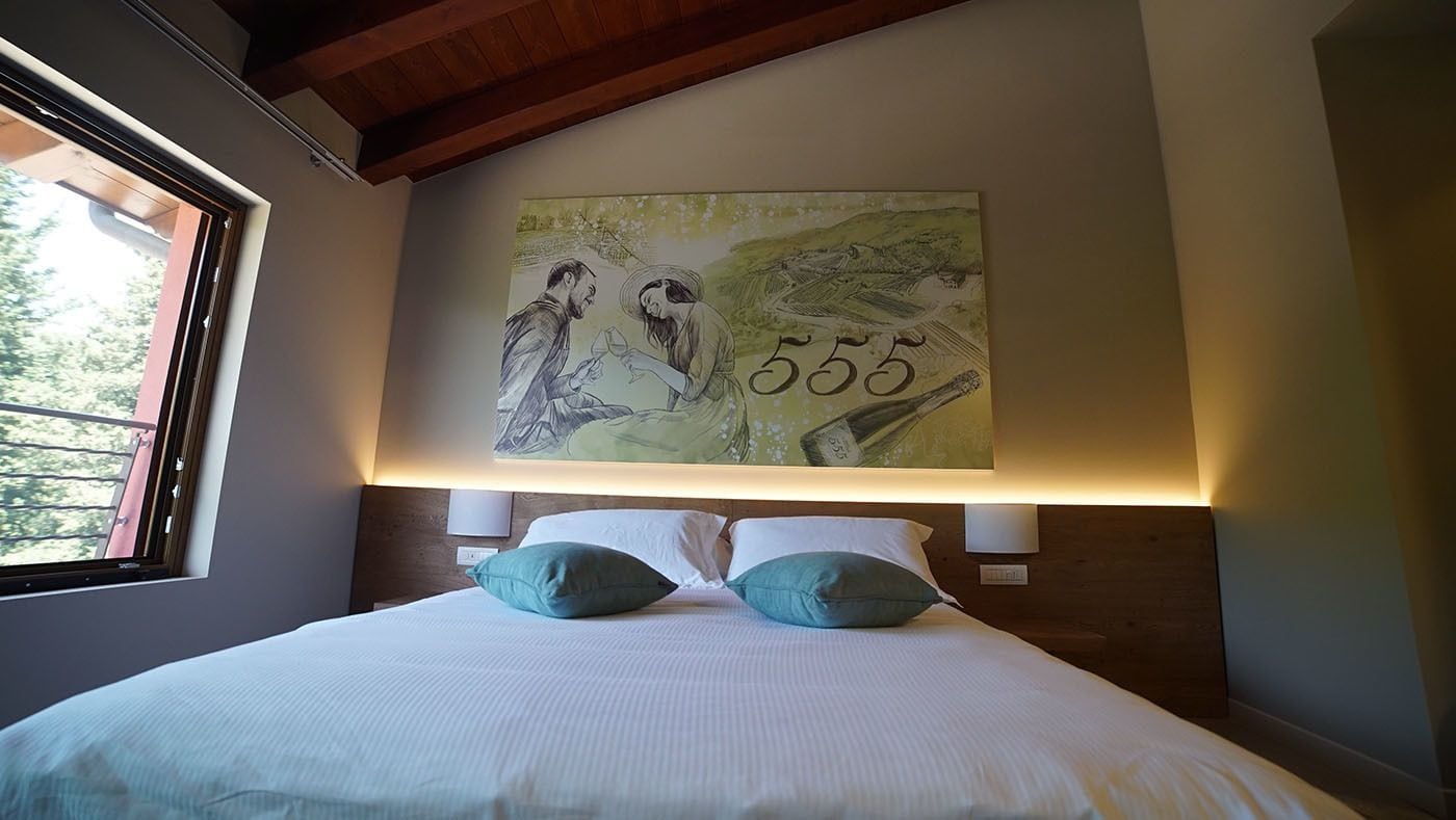 Un dormitorio con una cama grande, dos almohadas, una lámpara de pared y un cuadro sobre la cama.