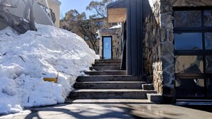 Una escalera cubierta de nieve que lleva a un edificio de piedra con una puerta azul.