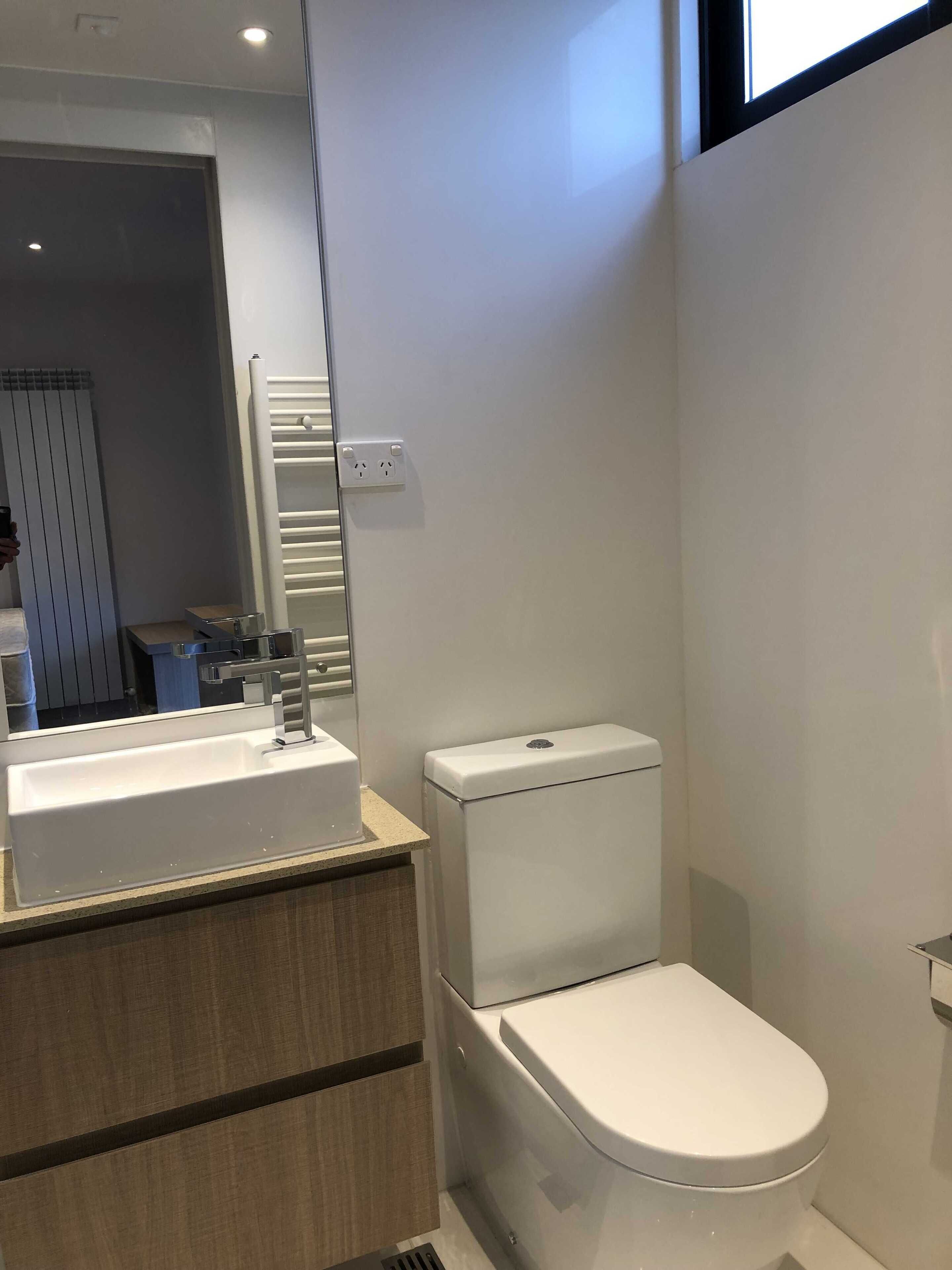 A modern bathroom with a white sink, a toilet, and a mirror.