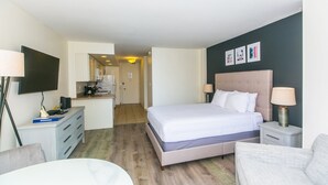 Une chambre d’hôtel équipée d’un lit, de tables de chevet, d’un bureau, d’une chaise et d’un téléviseur fixé au mur.