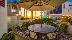 Un patio con una mesa redonda y sillas, una sombrilla y vistas a edificios en el fondo.