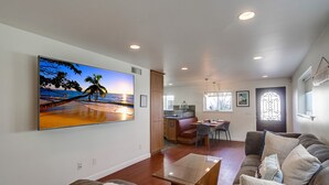 Una sala de estar amplia con un televisor de pantalla plana grande, una mesa de centro de madera y un sofá cómodo.