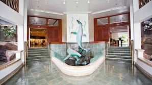 A lobby with a central fountain, a staircase, and a reception area.
