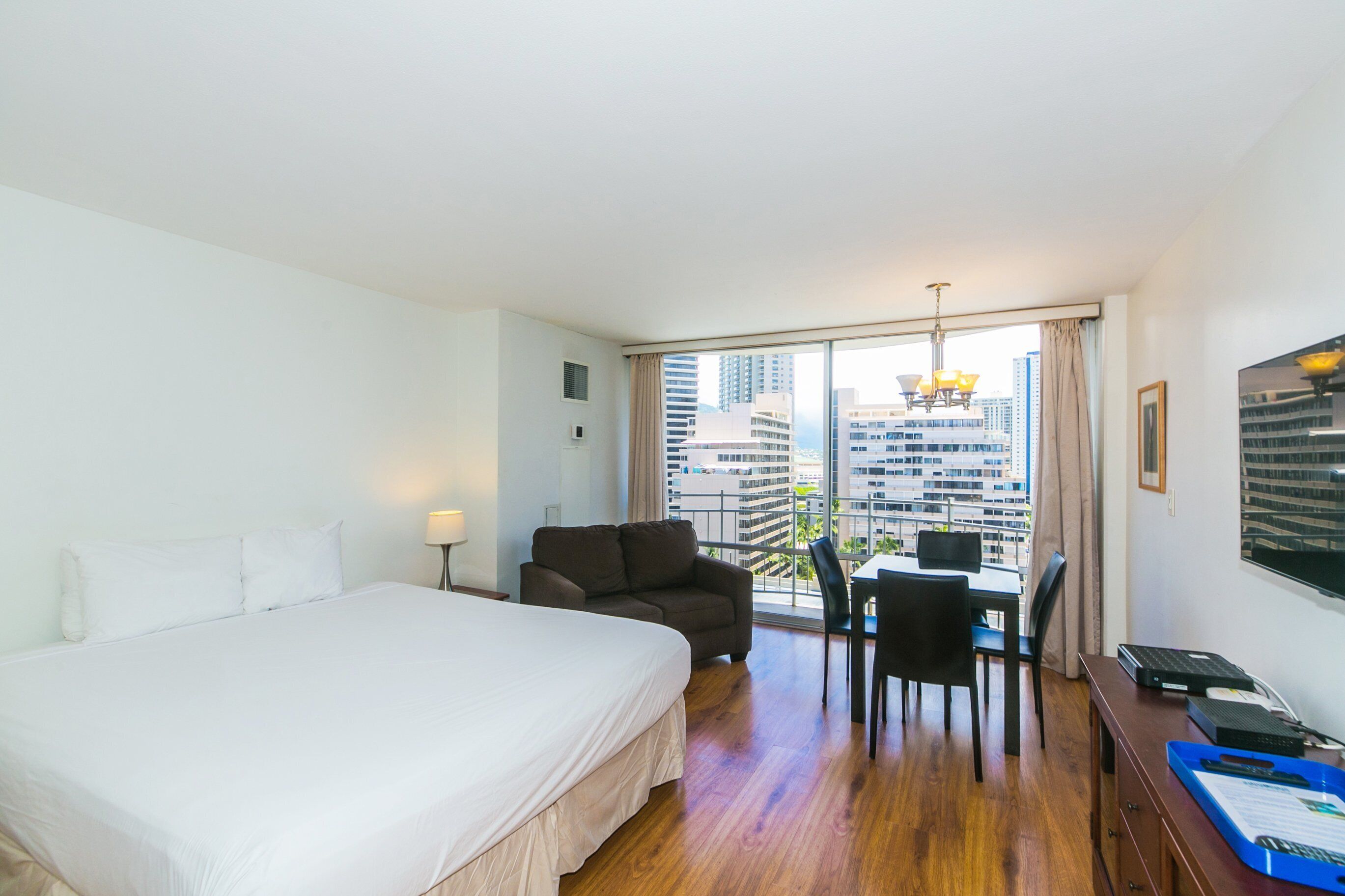 A hotel room with a large bed, a desk with a chair, and a view of tall buildings.