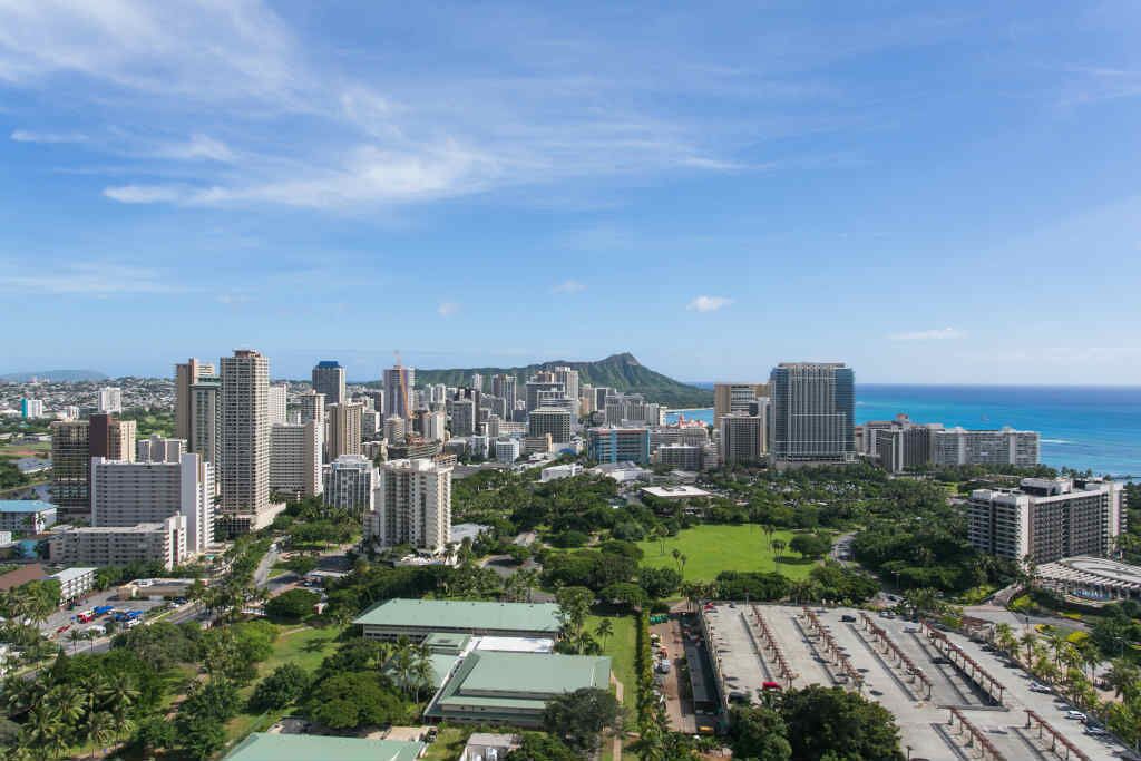 A cityscape with high-rise buildings, a large green park, and a view of the ocean.