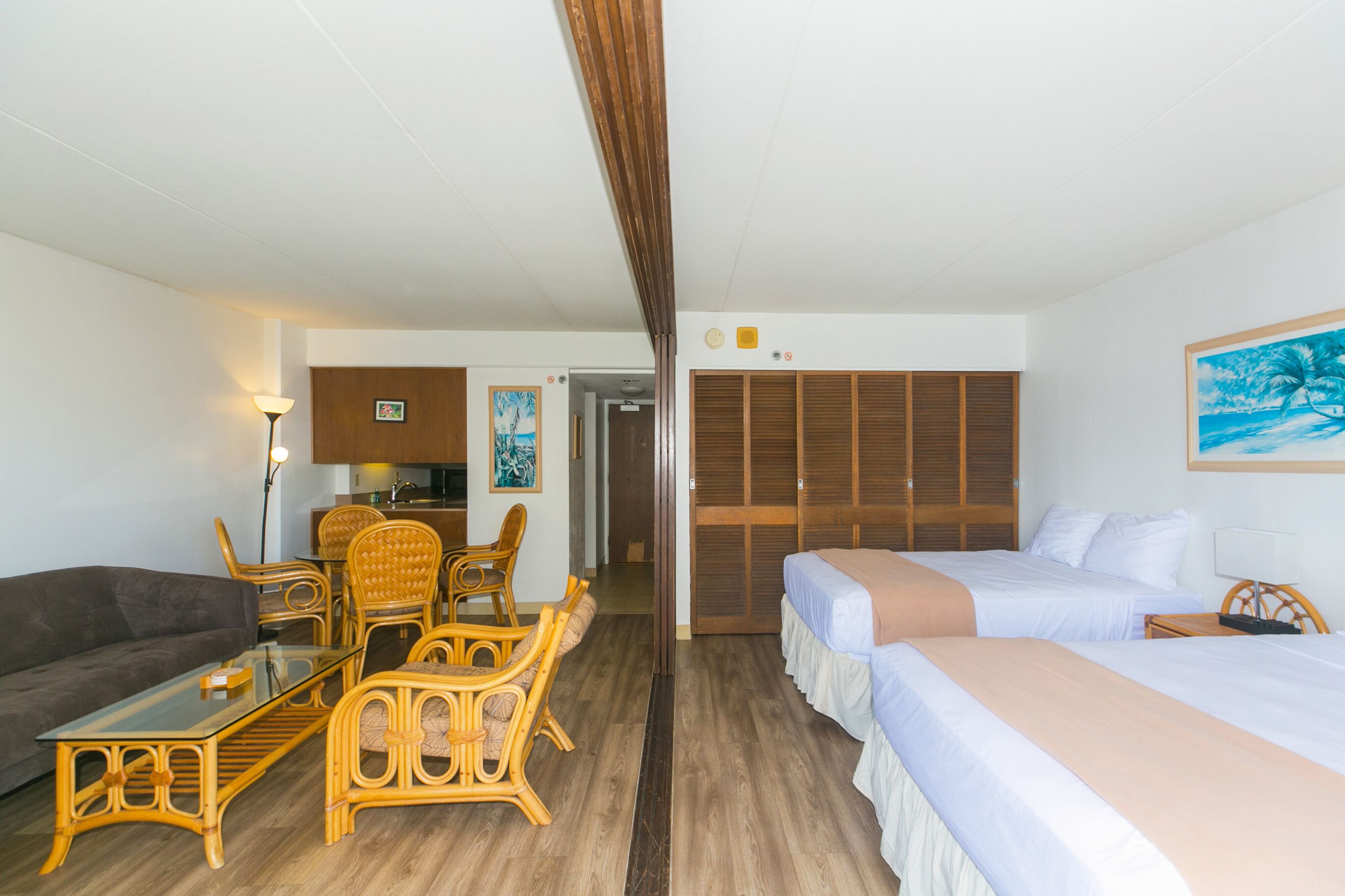 A hotel room with a dining area, a sofa, a bed, and a wooden wardrobe.
