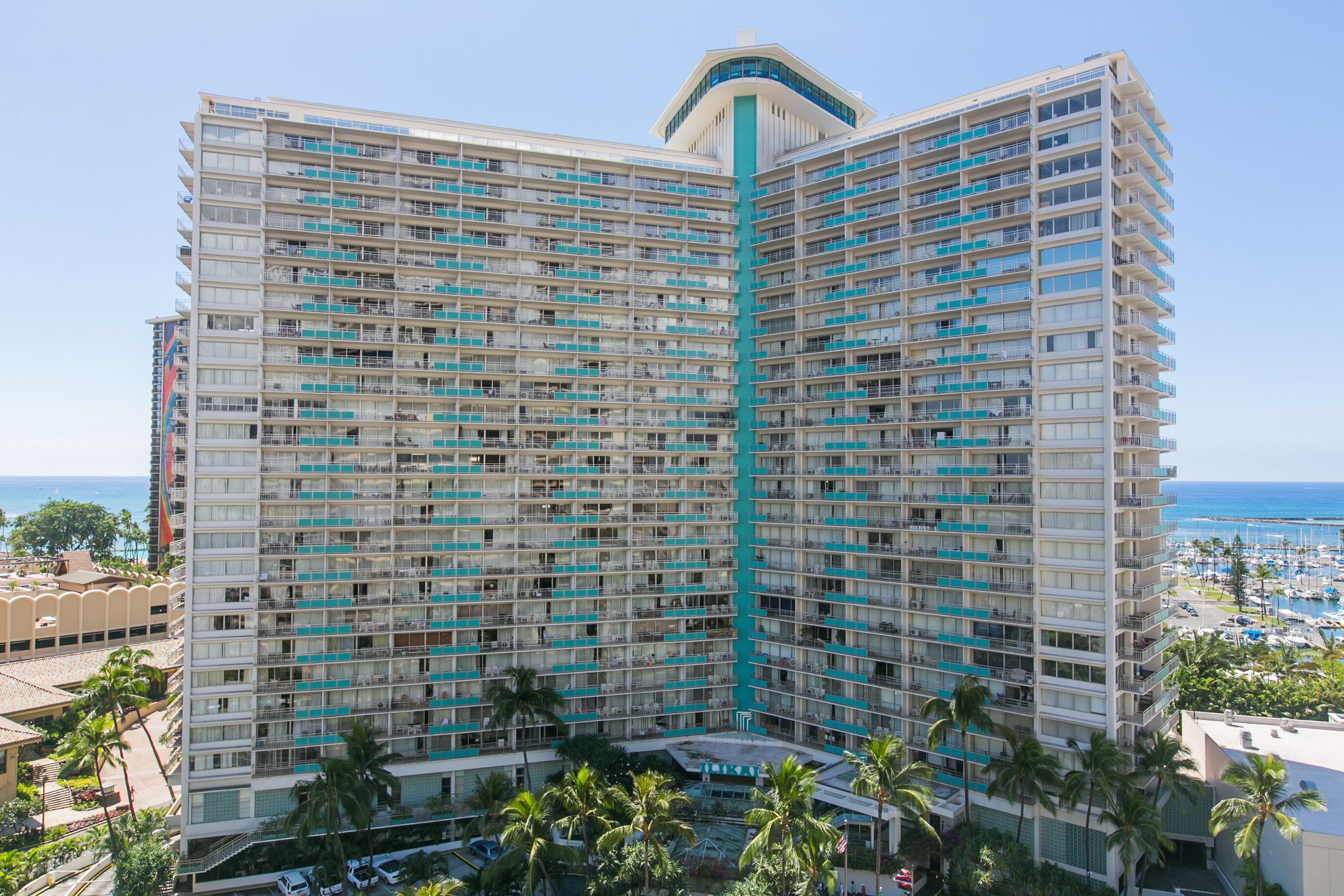 A high-rise hotel with multiple balconies, a central atrium, and a view of the marina and ocean.