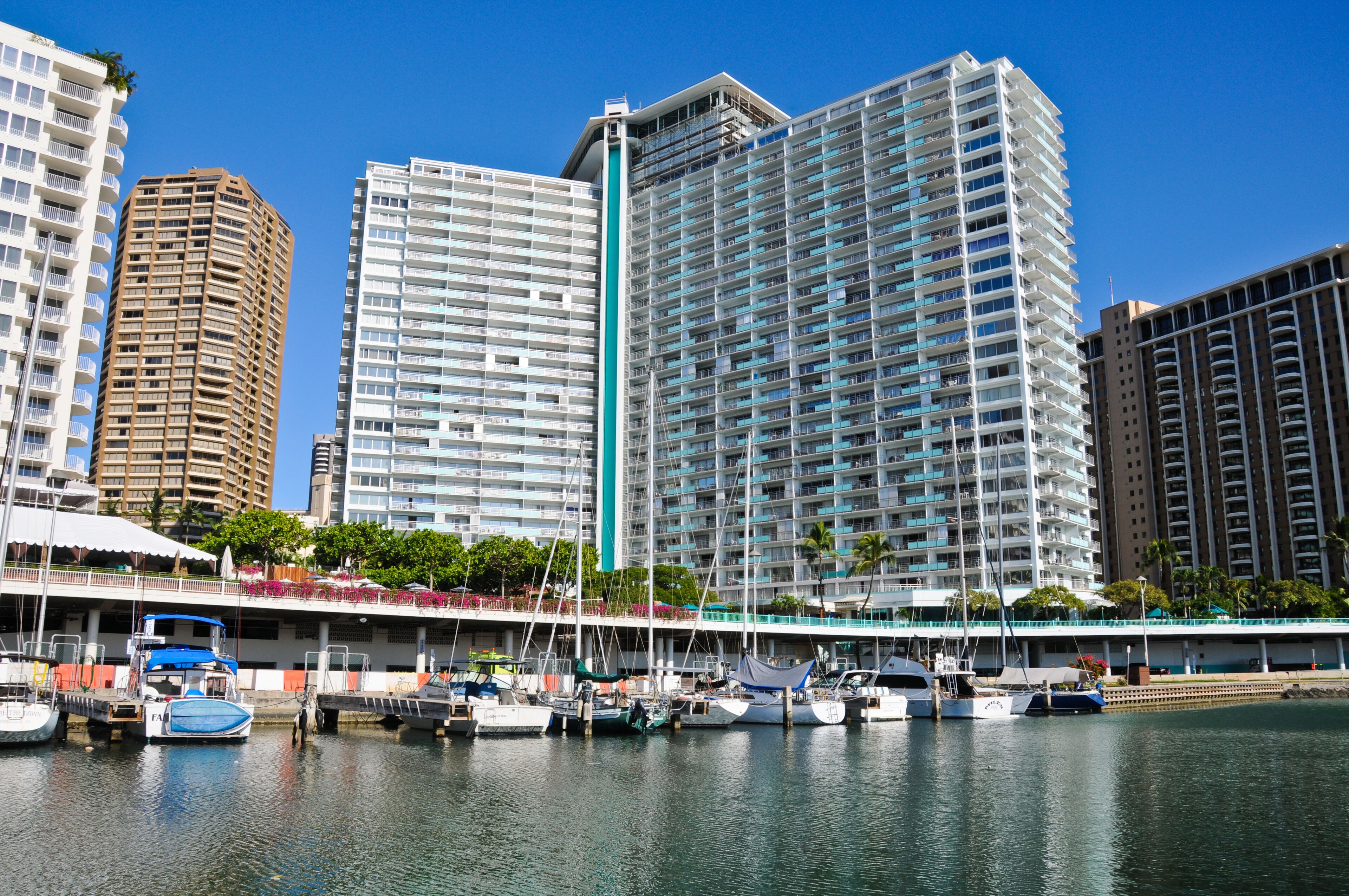 A marina with boats docked, surrounded by high-rise buildings.