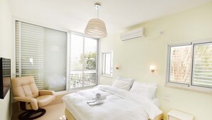 Une chambre à coucher comprenant un lit, une chaise, une table de chevet et une fenêtre avec des stores.