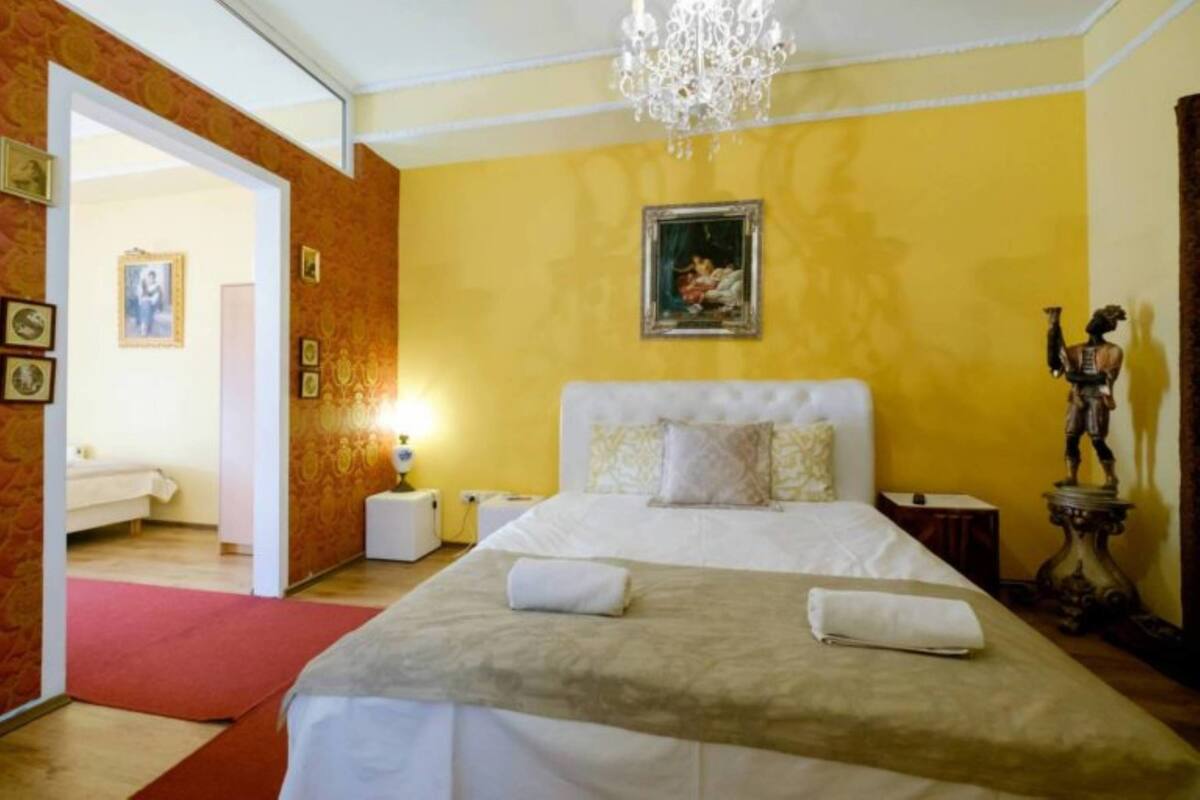A hotel room with a large bed, a chandelier, and a statue.