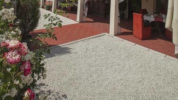 A two-story building with a covered patio area and a gravel driveway.