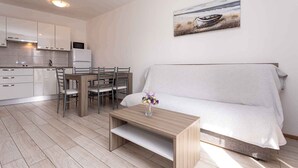 Una cocina moderna con armarios blancos y una zona de comedor con mesa y sillas de madera.
