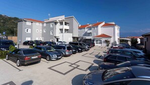 Un estacionamiento con varios autos y un edificio de varios pisos y techos rojos.