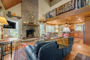 A spacious living room with a fireplace, a dining area, and a kitchen. - Orchard Park cottage (Versailles)
