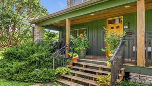A wooden house with a porch, stone pillar, and a yellow door. - Orchard Park cottage (Versailles)